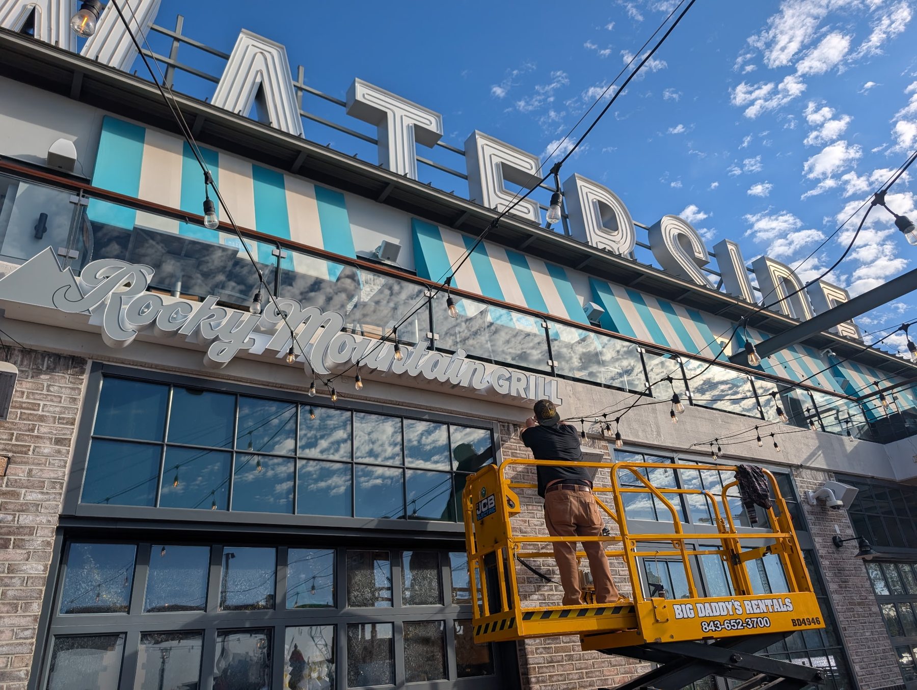Boom lift installing storefront channel letters on a coastal commercial building